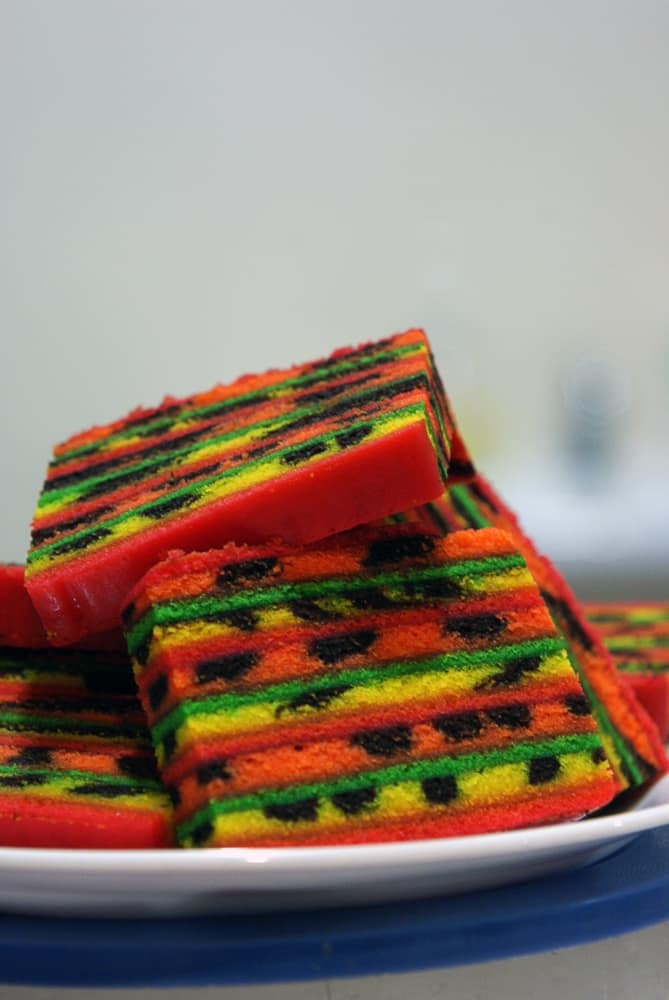 Slices of brightly layered kek lapis Sarawak stacked on a white plate