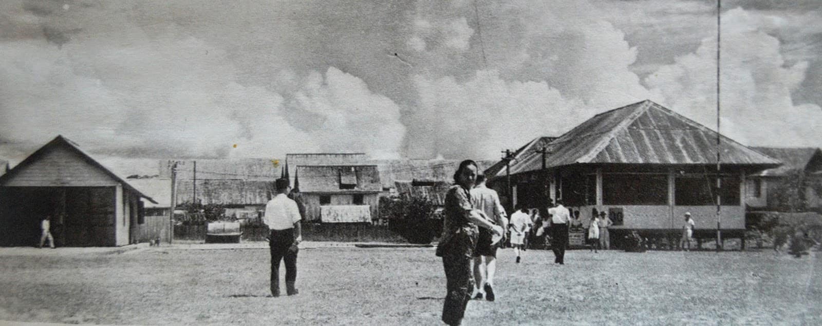 Picture shows passengers alighting from the plane and walking towards the old Bintulu airport departure/arrival hall (right). Private houses are shown in the background. The Bintulu airport building and private houses were both made of strong Belian wood.