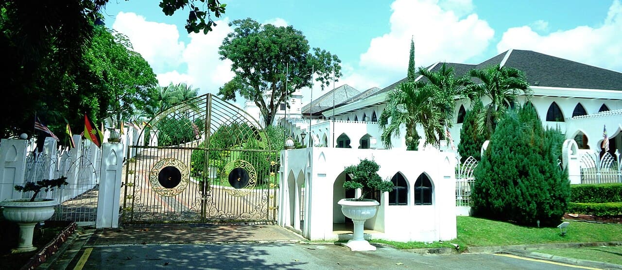 The white colonnaded facade and shingled roofs of the Astana above lawns on the north bank of the Sarawak River