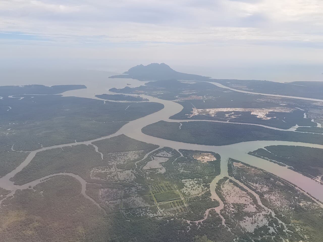 The Salak River winding through mangrove forest in Kuching Wetlands National Park with Mount Santubong beyond