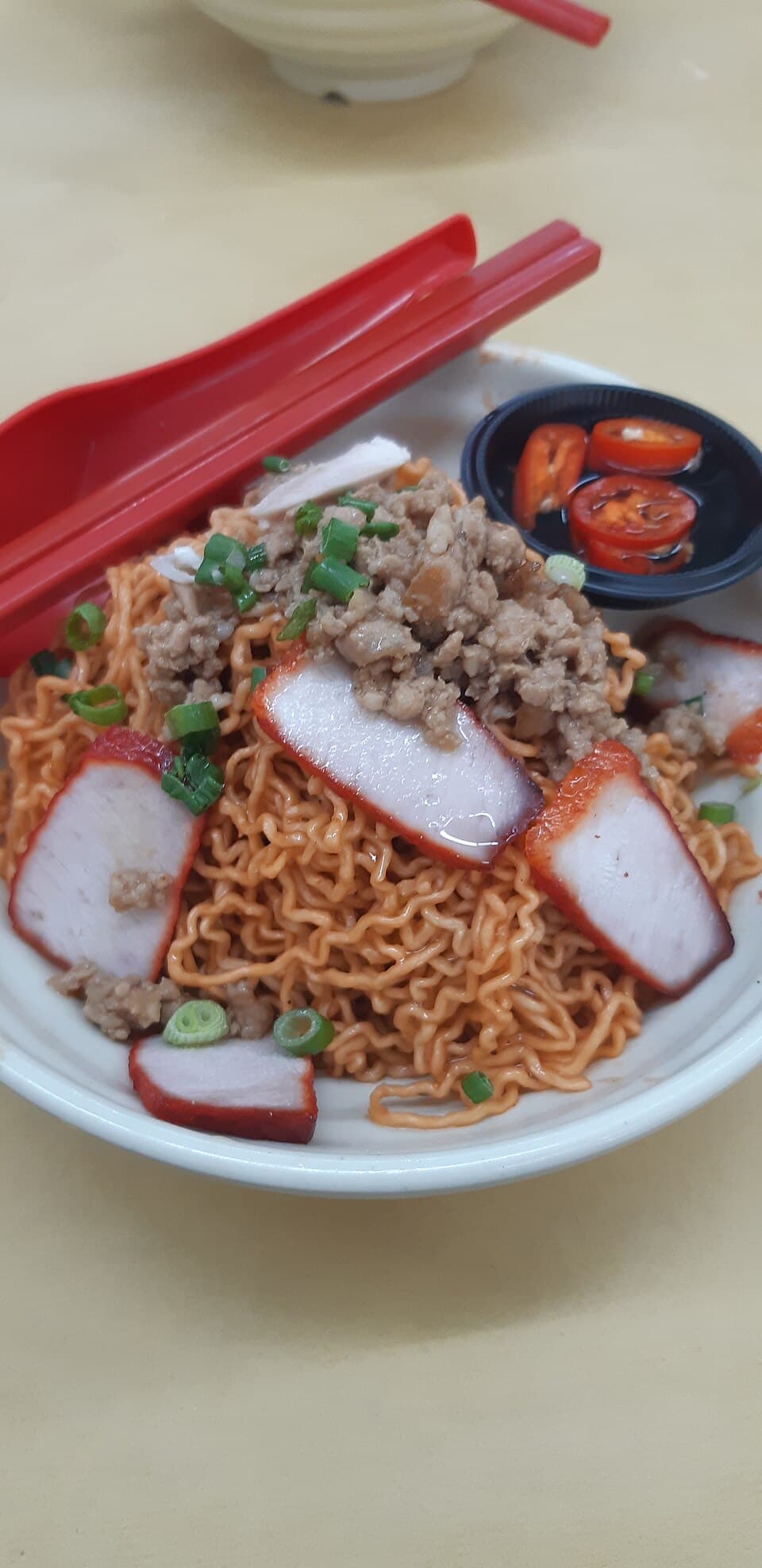 A plate of kolo mee, dry-tossed egg noodles topped with sliced char siu