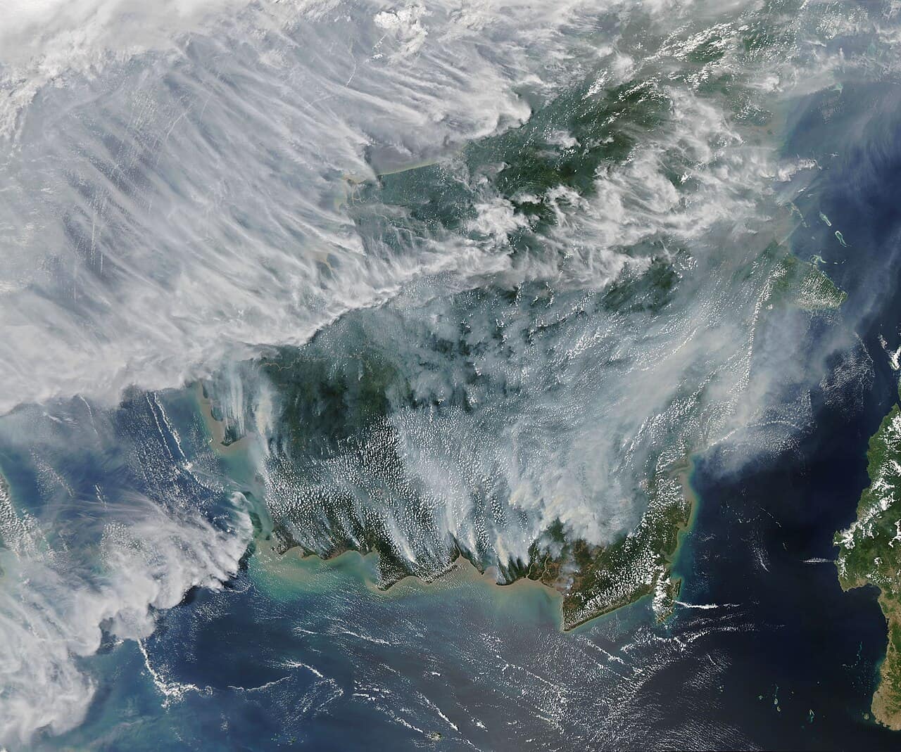 Satellite view of Borneo almost entirely obscured by grey smoke during the September 2019 haze, with fire hotspots visible across Kalimantan