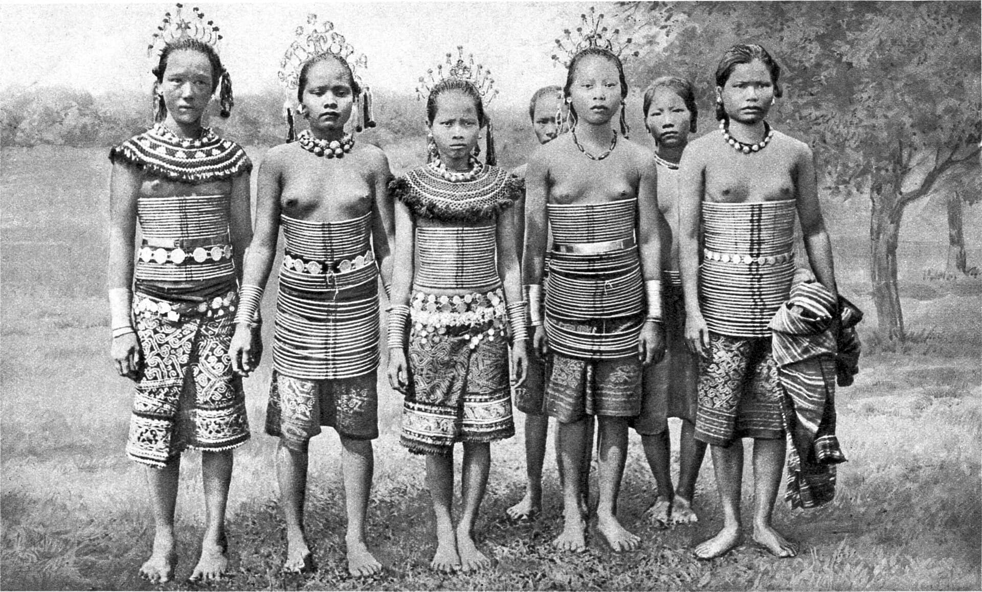 A ring-fenced garden of girls in the flower of youth. They are Sea Dayaks (Iban) from the Rejang district of Sarawak, and immensely proud of their rattan corsets gleaming with brass rings and filigree adornments. Note as the dress is not a uniform, as a common idea, but grow by degrees of the girl's