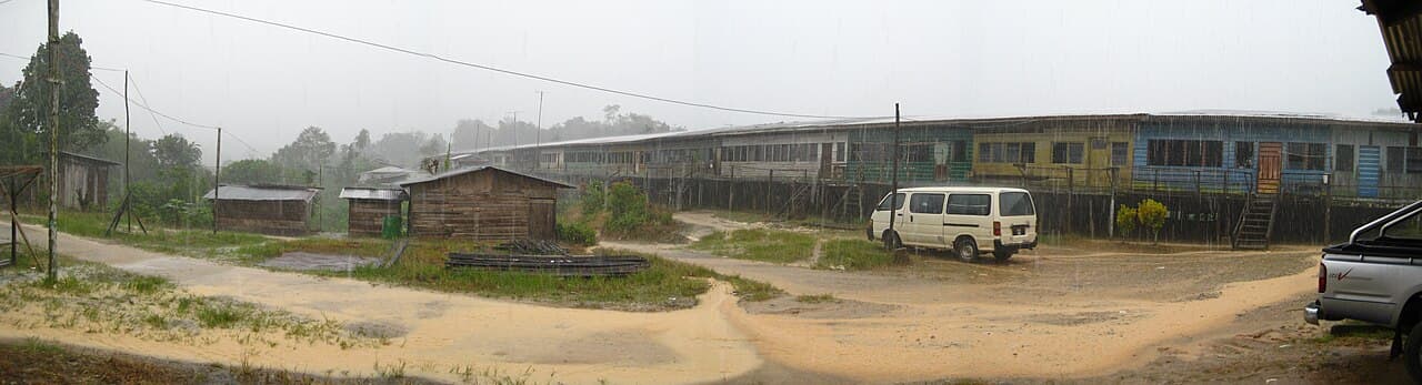 A timber Iban longhouse raised on stilts behind a swept open yard